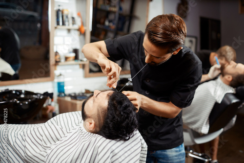 Hairdresser doing correction and cutting bread in modern barbershop.