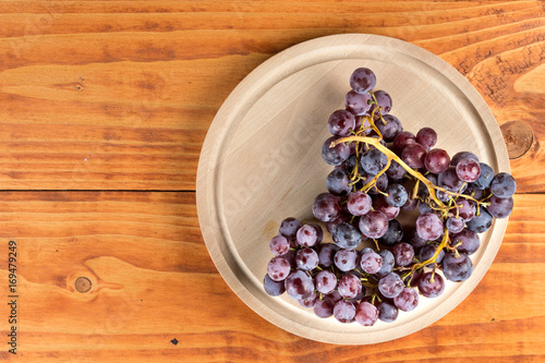 Fototapeta Naklejka Na Ścianę i Meble -  Flat lay above grapes on the round wooden kitchen board on the table