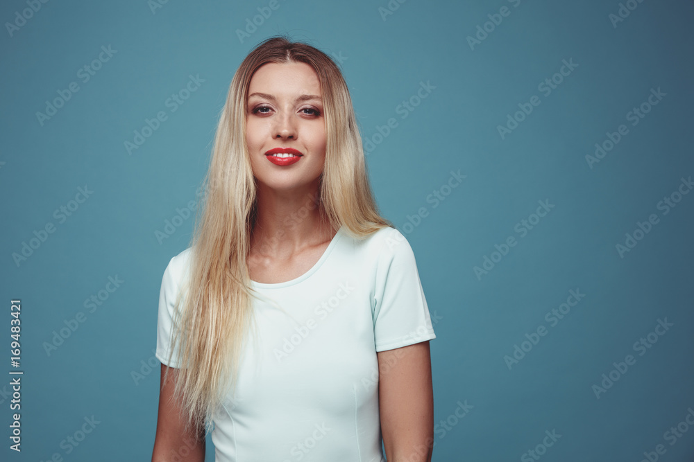Seductive young woman studio portrait close up on blue background. Skin care and beauty concept. Classic make up. Long blond hair girl . Seductive young woman studio portrait close up on blue background. Skin care and beauty concept. Classic make up. Long blond hair girl .