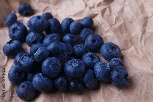 Blueberries on rustic wooden background, close up. Delicious berries on craft paper, macro