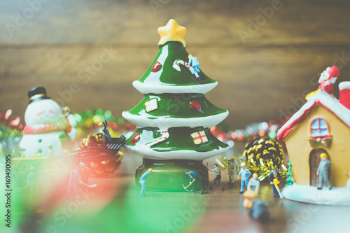 Creative concept with miniature people creating Christmas decorations on a wooden background.