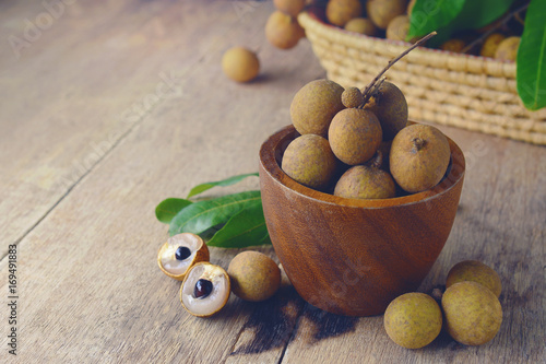 Fresh longan fruit with peel the skin show white meat and black seed on a wooden background. photo