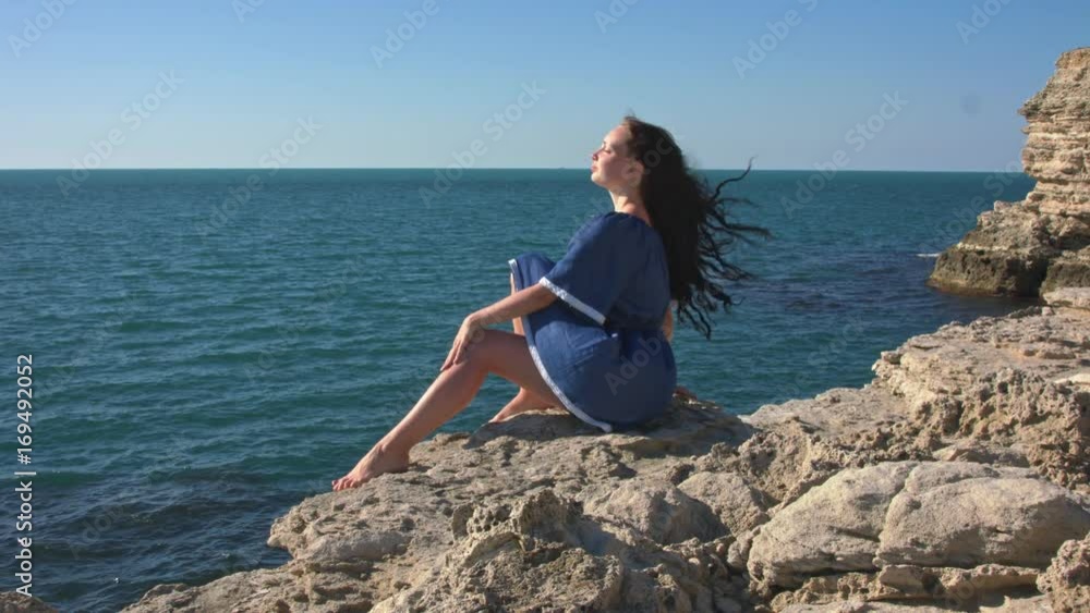 The girl in the blue dress sitting by the sea. A strong wind The girl in the blue dress sitting by the sea. A strong wind