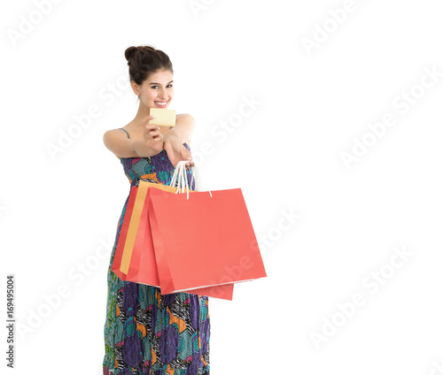Young beautiful woman with credit card in hand and holding shopping bags over white background