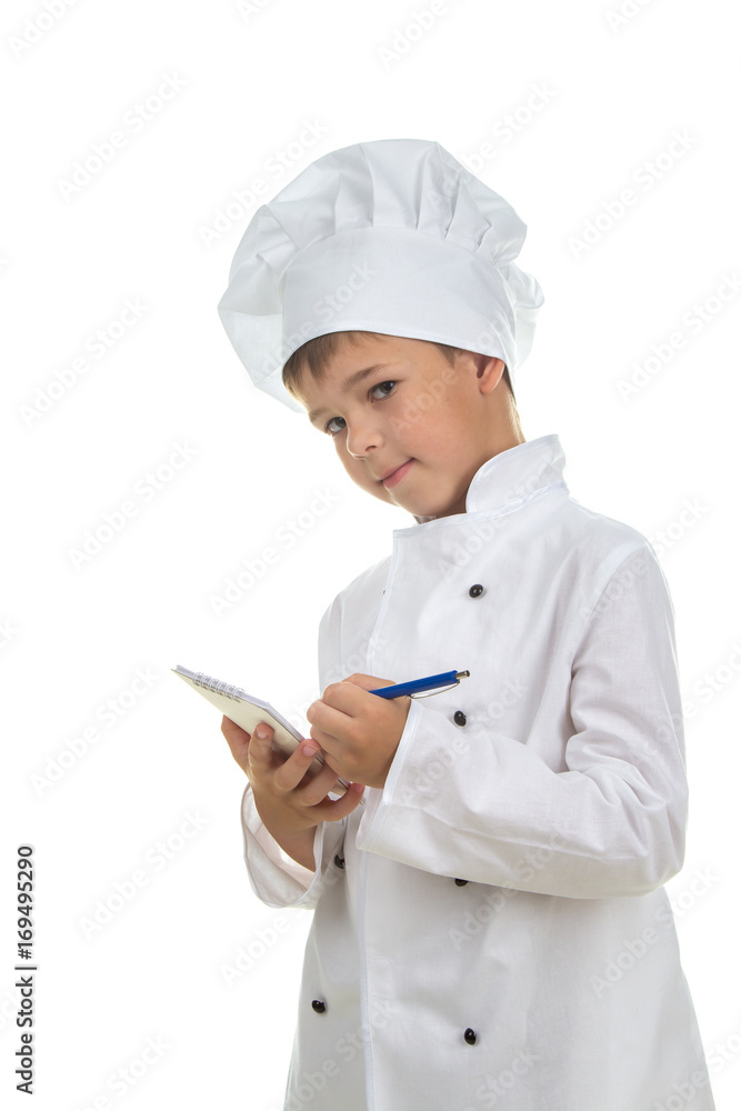 Cute boy chef writes down a recipe into a notebook, on white background. Cute boy chef writes down a recipe into a notebook, on white background.