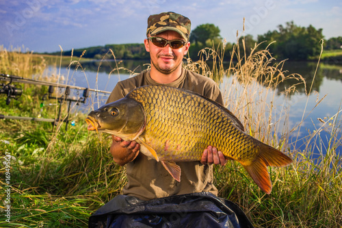 Happy angler with carp fishing trophy.Fish trophy