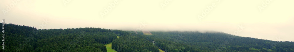 Naklejka premium Spływające chmury po zboczu wzgórza; potok mgły bieli