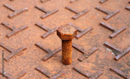 Rusty metal bolt put on the steel plate floor in brown color with rusty iron. rust is a reddish or yellowish-brown flaky coating of iron oxide that is formed on iron by oxidation.