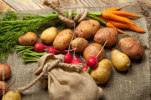 Potatoes  radishes and carrots on a rustic wooden background