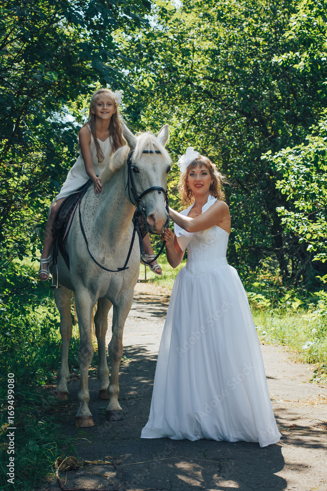 Bride, small girl and white horse in the park