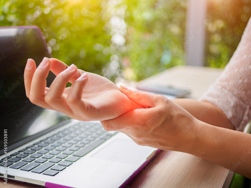 Fototapeta Zbliżenie kobieta trzyma jej bolesną rękę od używać komputer. Zespół biurowy odczuwa ból ręki przez chorobę zawodową.