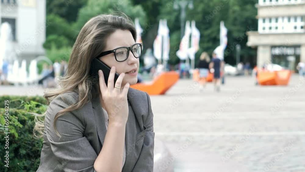 Attractive businesswoman speaking on cellphone while sitting in the square, steadycam shot
Attractive businesswoman speaking on cellphone while sitting in the square, steadycam shot