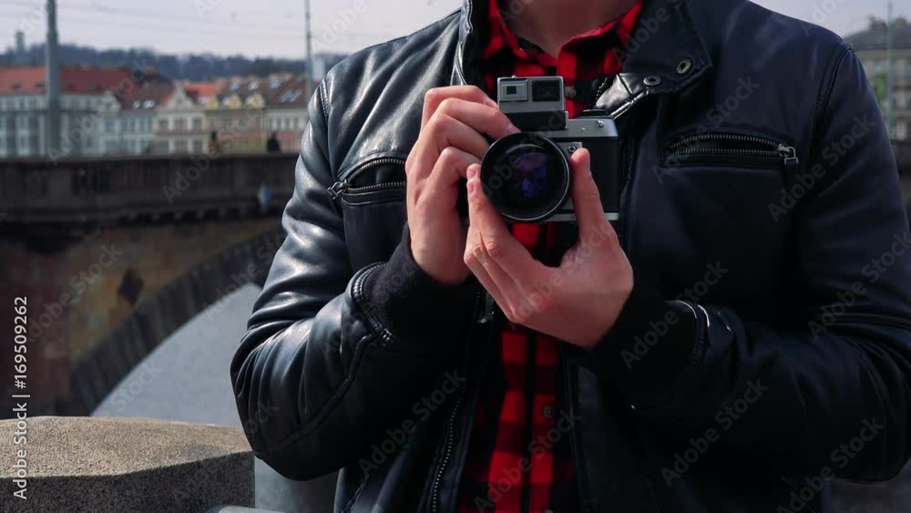 A man holds a camera against his chest in an urban area - closeup A man holds a camera against his chest in an urban area - closeup