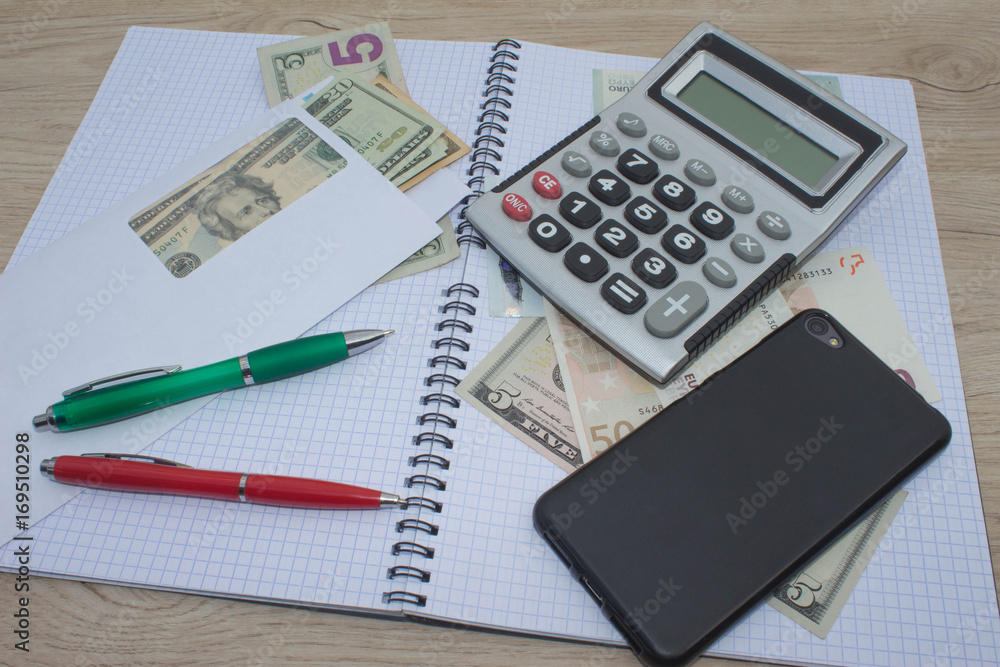 Photo shows a closeup of business calculator and money on a paper Photo shows a closeup of business calculator and money on a paper