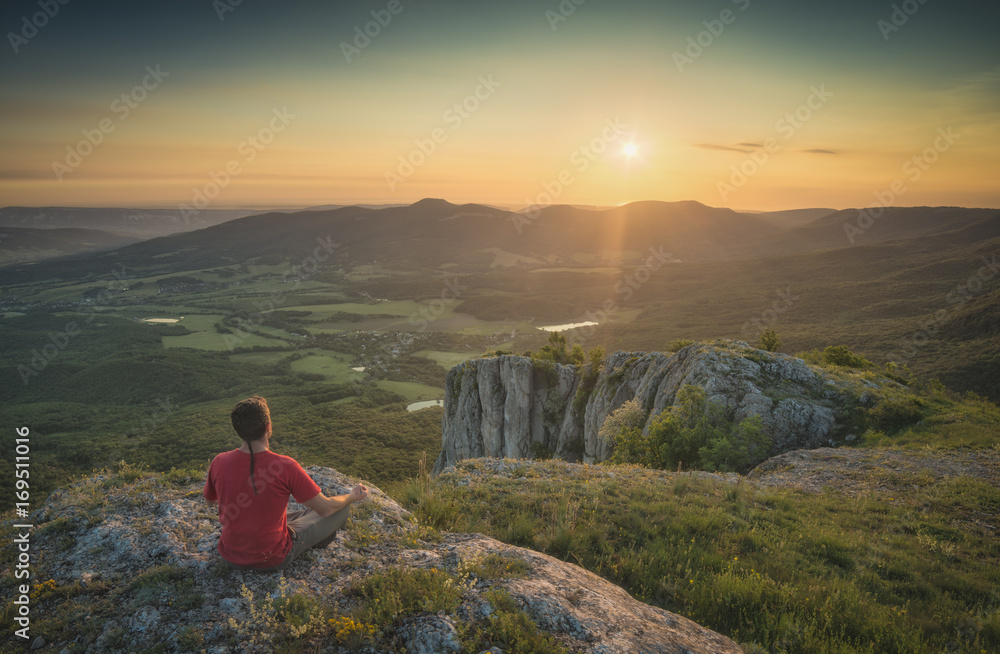 Fototapeta premium Tourist sitting on a rocky hill