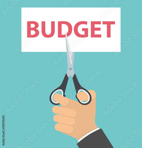 Budget cut concept. Hand cutting a paper with red budget text on it