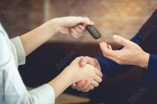 The woman holding the key of the car has agreed to give the customer.