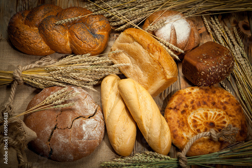 Rustic bread and wheat on the wooden background.