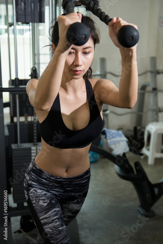 Young asian woman in sportswear workout training with machine.