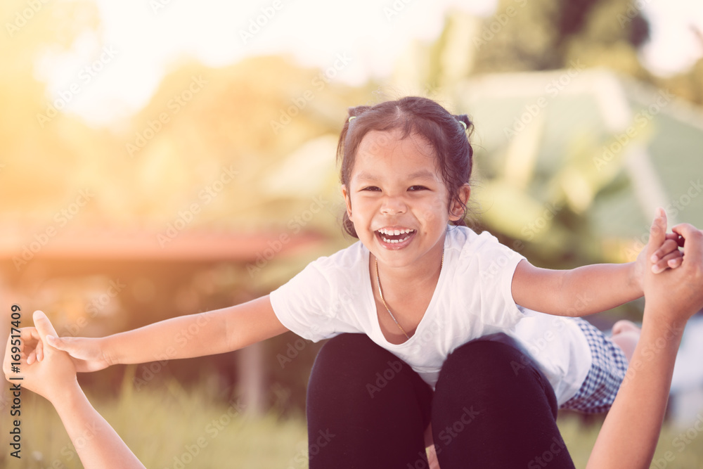 Happy asian child girl laughing and having fun to play with her mother in the park in vintage color tone Happy asian child girl laughing and having fun to play with her mother in the park in vintage color tone