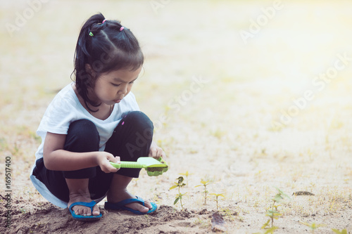 Cute asian little child girl having fun to play with sand in playground