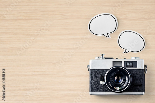 Business concept - Top view of modern office wood desktop background with blank bubble sticker and vintage camera for mockup design and copy space