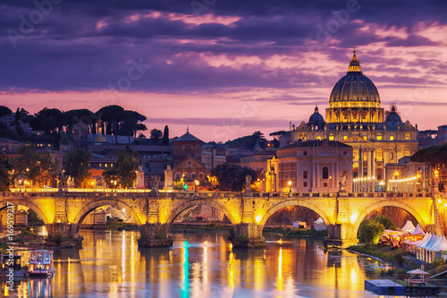 Night view of old Sant' Angelo Bridge and St. Peter's cathedral in Vatican City Rome Italy.