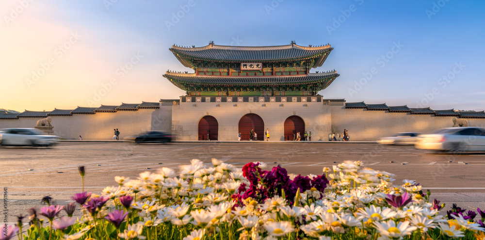 Fototapeta premium Pałac Gyeongbokgung z kwietnikiem na pierwszym planie W Korei Południowej, z nazwą pałacu „Gyeongbokgung” na znaku