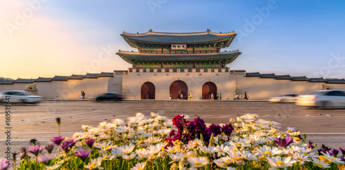 Gyeongbokgung Palace with flowers bed in foreground In South Korea, with the name of the palace 'Gyeongbokgung' on a sign