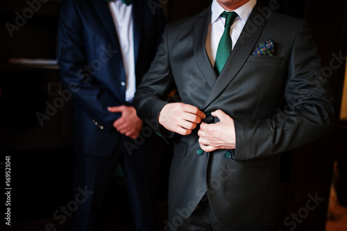 Groom dressing up in the presence of his groomsmen in the room.