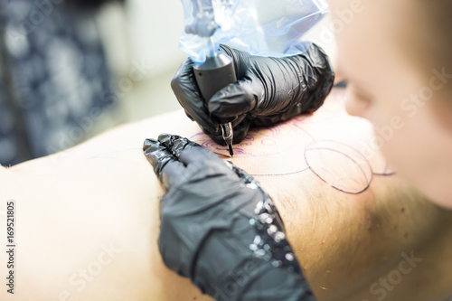 Professional tattooer make the tattoo with gloves on by special tool close up.