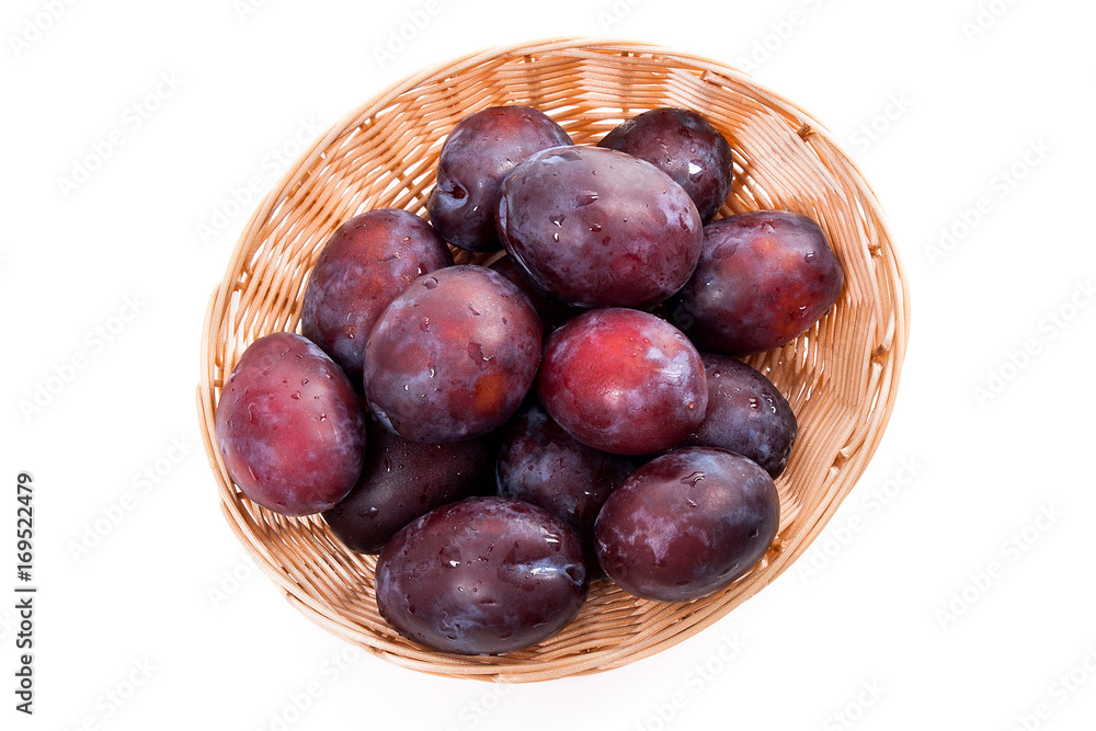 Yellow wooden basket with ripe plums isolated on a white background.. Yellow wooden basket with ripe plums isolated on a white background..