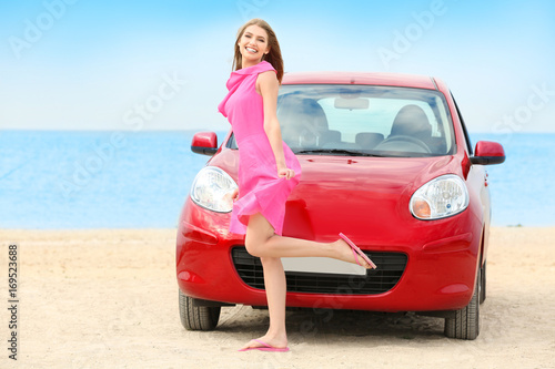 Beautiful young woman near car at sea resort