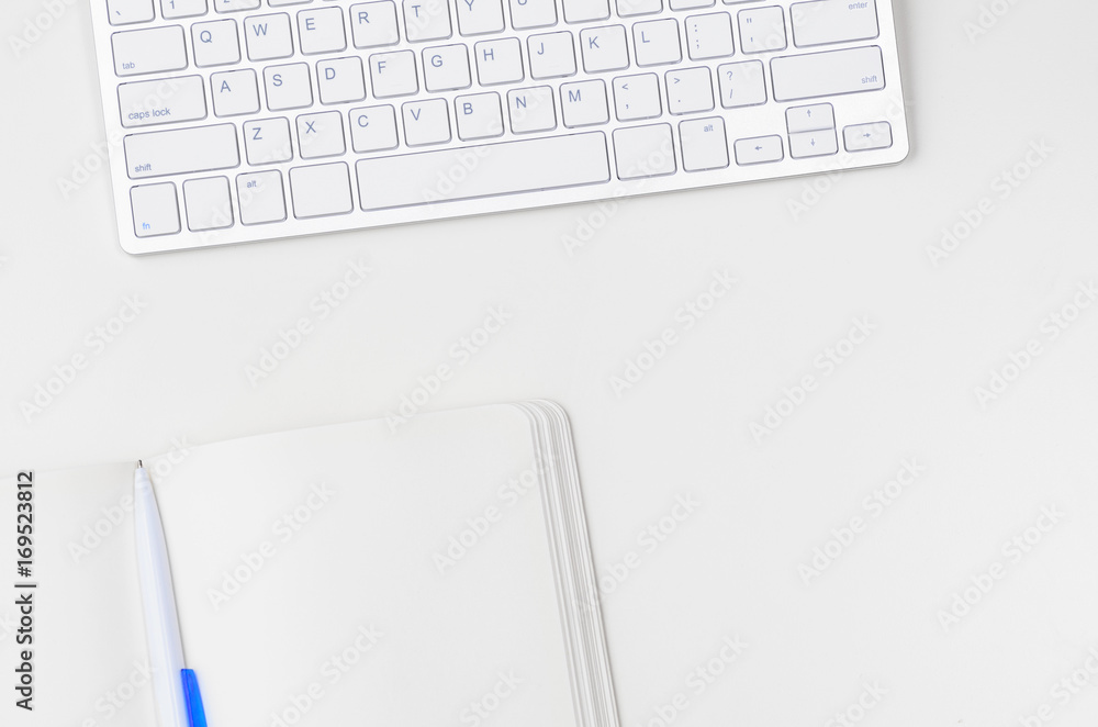 White workplace with keyboard and notebook, view from above White workplace with keyboard and notebook, view from above