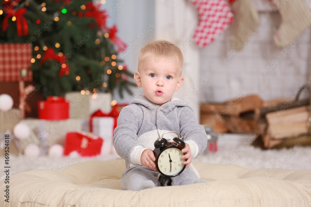 Cute little baby with clock at home. Christmas countdown concept