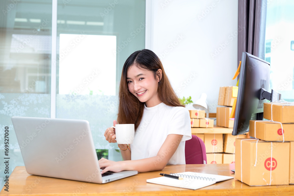 Young asian girl freelancer small business private working at home office with laptop, note, coffee, packaging delivery online market on purchase orders to customer. Young asian girl freelancer small business private working at home office with laptop, note, coffee, packaging delivery online market on purchase orders to customer.