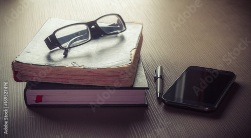 Eyeglass and Old bible book on wooden desk