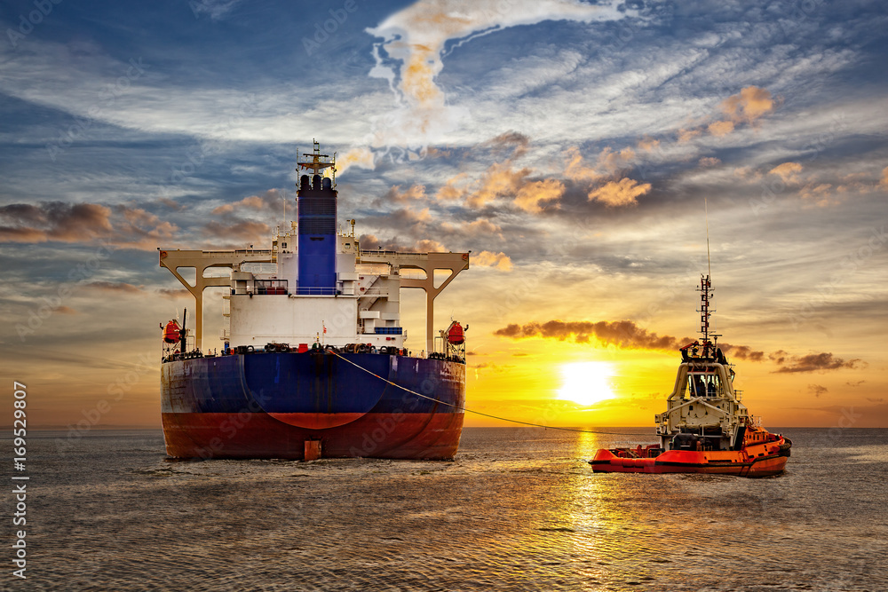 Tanker and tugboat on sea at sunset. - obrazy, fototapety, plakaty 