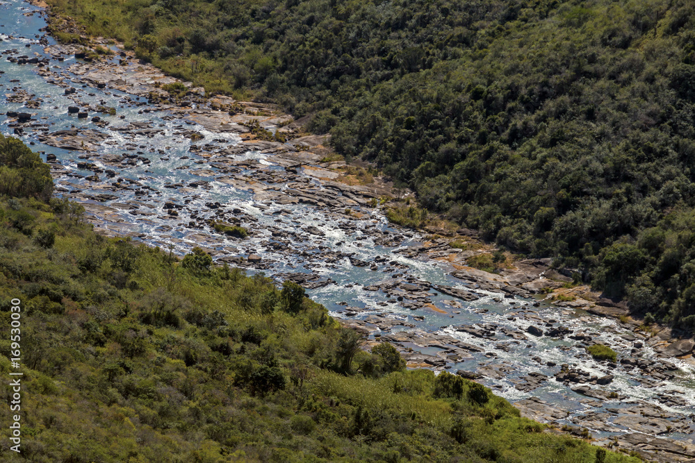 Fototapeta premium River Flowing Through Winter Vegetation Lined Valley