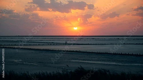 Time lapse of colorful scenic sunset at Syvash lake with beautiful boiling sunlit cumulus clouds moving in orange and yellow sky. Shot in Pryozerne village, Kherson oblast, Ukraine photo