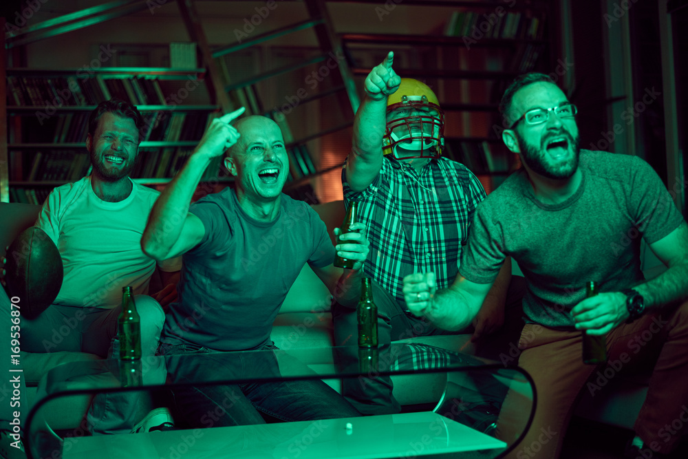 Four men watching american football game on television