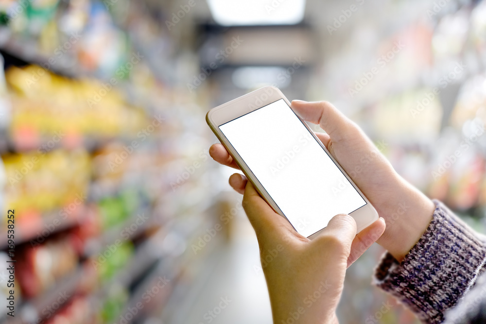 woman using smartphone in supermarket Blank screen mobile phone for graphic display montage. woman using smartphone in supermarket Blank screen mobile phone for graphic display montage.