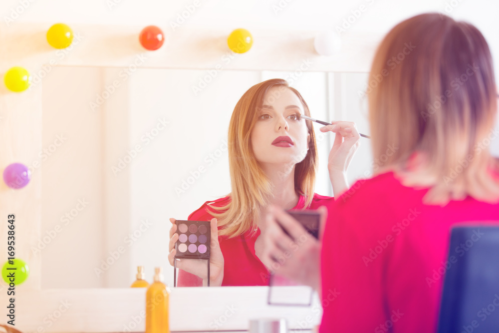 Young caucasian woman applying cosmetics