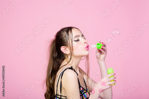 woman with bubble blower on pink studio background