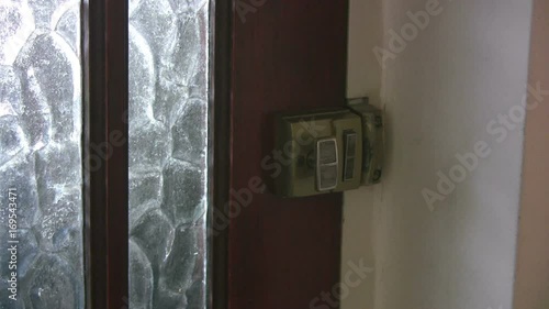 Close up interior shot of a man arriving at a house by the front door. The door is opened by a young woman to let him in. The door has frosted glass panes and a Yale type lock.