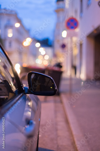 Rückspiegel eines parkenden Autos am Abend, Straße