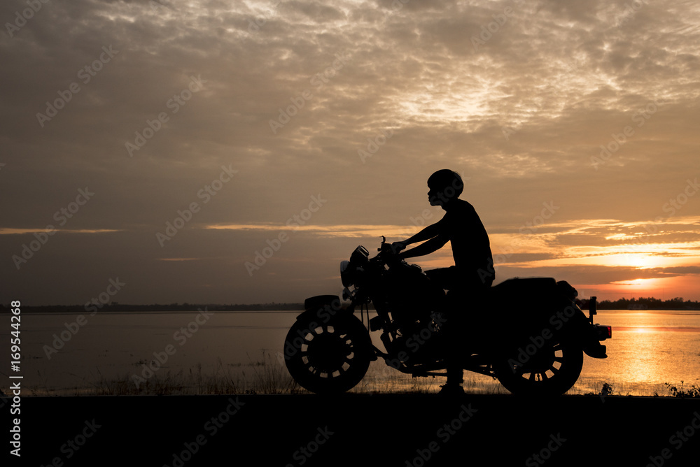 Fototapeta premium Silhouette man riding motor bike with sunset. Travel Concept