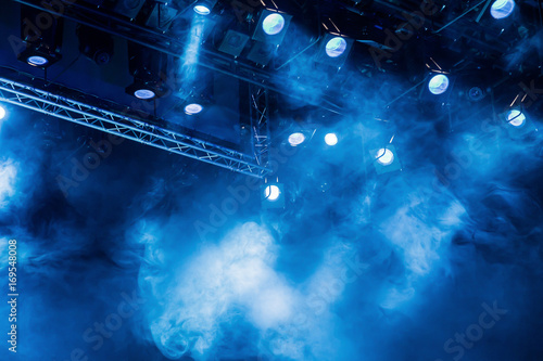 Blue light rays from the spotlight through the smoke at the theater or concert hall. Lighting equipment for a performance or show.