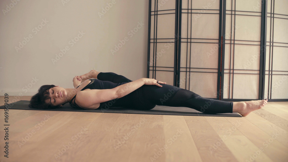 A young woman performing yoga-asanas in the hall.