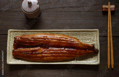 a plate of grilled eel with sweeten soy sauce on wooden background photo